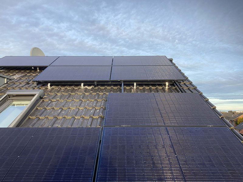 Dach mit mehreren Solarmodulen unter bewölktem Himmel.